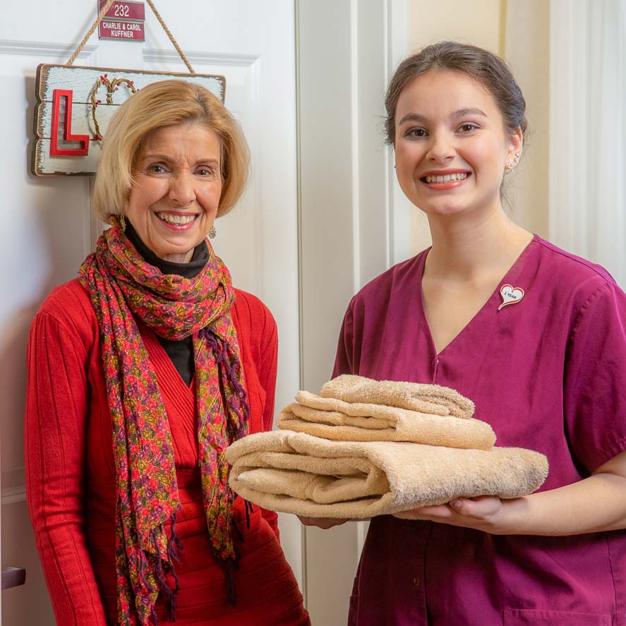 A team member delivering fresh linens to a resident at Stoneybrook Lodge